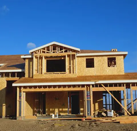 A house under construction with some wood on the front.