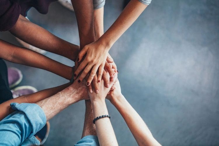 A group of people holding hands in the middle of a circle.