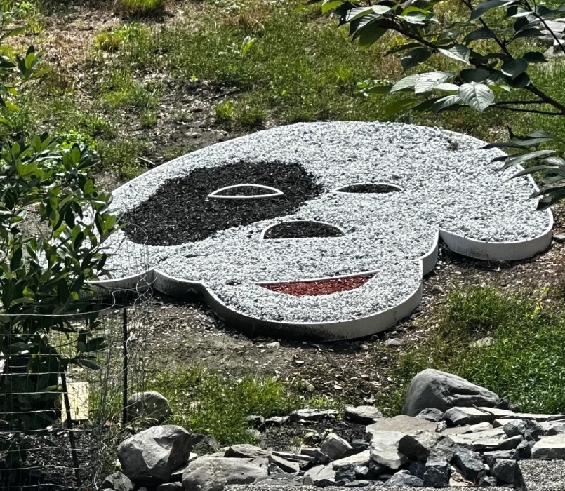 A stone sculpture of a dog 's face in the grass.